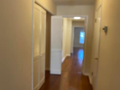 Hallway featuring dark wood-style floors and baseboards