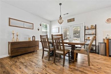 Dining area featuring wood finished floors, baseboards, french doors, and a chandelier