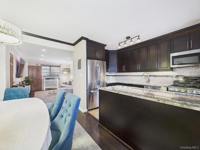 Kitchen featuring light stone counters, dark brown cabinets, appliances with stainless steel finishes, dark wood finished floors, and open floor plan
