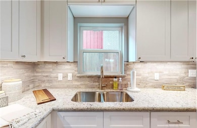 Kitchen with a sink, white cabinets, decorative ba