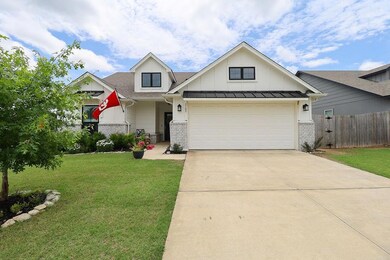 View of front of house featuring brick siding, concrete driveway, a garage, board and batten siding, and a shingled roof