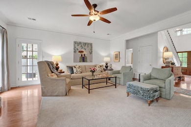 Living room with crown molding, plenty of natural light, a ceiling fan, and wood finished floors