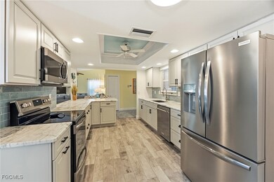 Kitchen with stainless steel appliances, tasteful backsplash, light wood-style flooring, a tray ceiling, and leather finish granite countertops