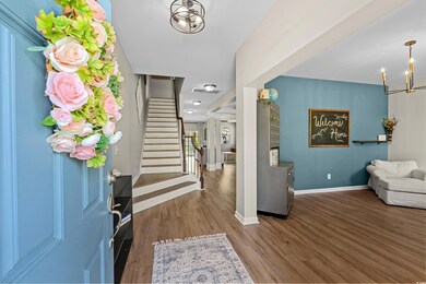 Foyer entrance featuring stairs, a notable chandelier, baseboards, and wood finished floors