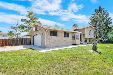 Tri-level home with brick siding, a garage, concrete driveway, and entry steps