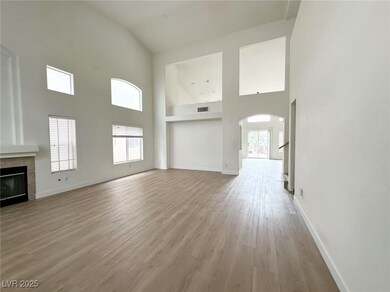 Unfurnished living room with a tiled fireplace, light wood-style floors, high vaulted ceiling, and arched walkways