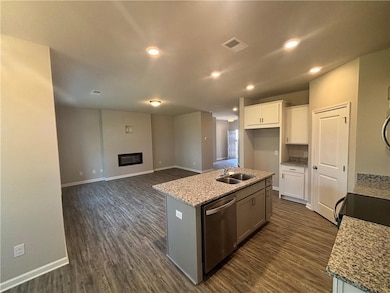 Kitchen with dark wood-style floors, white cabinetry, dishwasher, a center island with sink, and recessed lighting