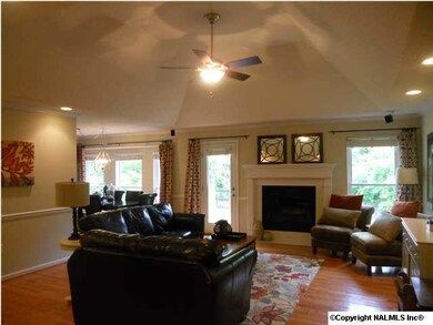 The large open family room features a vaulted trey ceiling, recessed lighting, beautiful hardwood floors, a ceiling fan and fireplace.