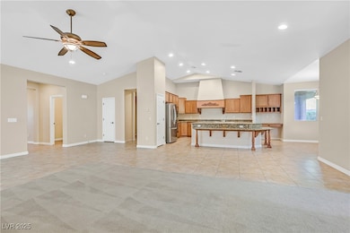 Kitchen featuring light tile patterned floors, open floor plan, a kitchen bar, a kitchen island with sink, and light carpet