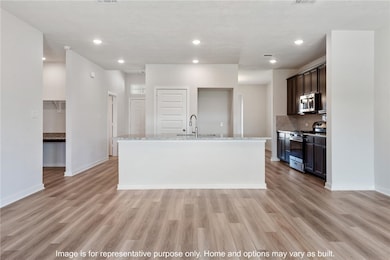 Kitchen featuring decorative backsplash, a kitchen island with sink, recessed lighting, stainless steel appliances, and light stone counters