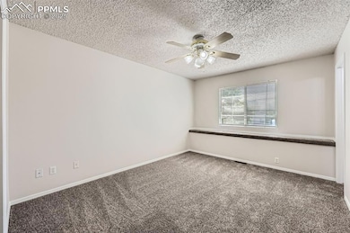 Spare room with ceiling fan, carpet flooring, a textured ceiling, and baseboards