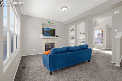Carpeted living area with a tile fireplace, visibl