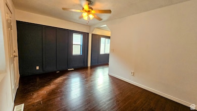 Unfurnished bedroom with a textured ceiling, dark wood-style flooring, and a ceiling fan