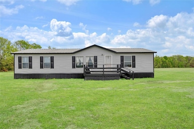 Manufactured / mobile home with a wooden deck, a front yard, and a metal roof
