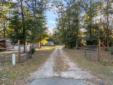 The charming guest home, welcoming visitors at the property's entrance, gracefully precedes the main residence nestled further beyond.