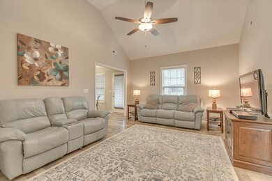 Vaulted living room with ceiling fan and wood laminate floors