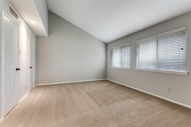 Spare room featuring vaulted ceiling, light carpet, and recessed lighting
