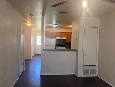 Kitchen with freestanding refrigerator, brown cabinetry, a ceiling fan, dark countertops, and a textured ceiling