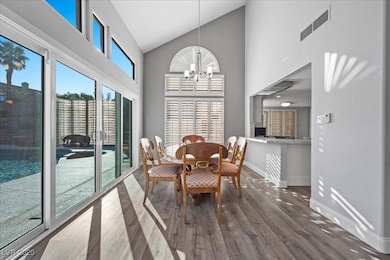 Dining area featuring high vaulted ceiling, a chandelier, and dark wood-style floors