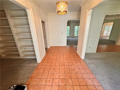 Corridor with light carpet, light tile patterned floors, a chandelier, and ornamental molding