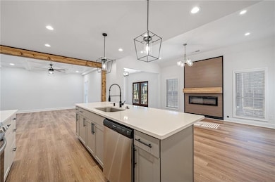 Kitchen with open floor plan, stainless steel dishwasher, gray cabinetry, and a sink