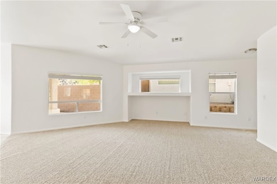 Carpeted empty room with baseboards, ceiling fan,