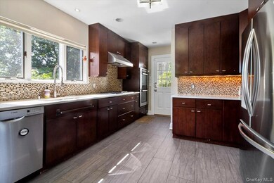 Kitchen featuring appliances with stainless steel finishes, light countertops, under cabinet range hood, and dark brown cabinets