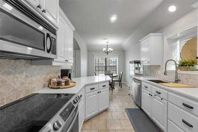 The kitchen features modern appliances, white cabi