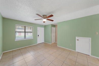 Spare room featuring light tile patterned floors, a textured ceiling, and ceiling fan