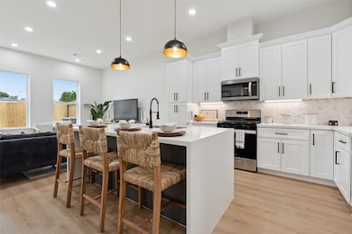 Indulge your culinary dreams in this chef's haven, where abundant cabinet space meets exquisite design elements. An oversized quartz waterfall island takes center stage, adorned with a designer backsplash that adds a touch of glamour to every meal preparation.