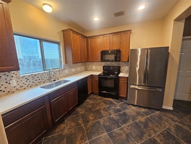 Kitchen featuring black appliances, light counter