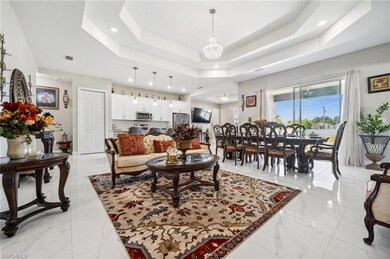 Living room with a raised ceiling, light marble finish floors, and recessed lighting