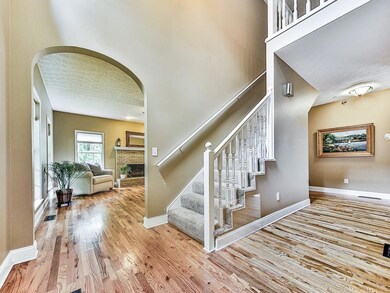 Staircase with arched walkways, wood finished floors, a brick fireplace, and a textured ceiling