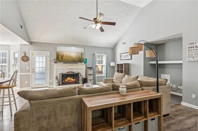 Living room with vaulted ceiling, ceiling fan, a textured ceiling, dark wood-type flooring, and a fireplace