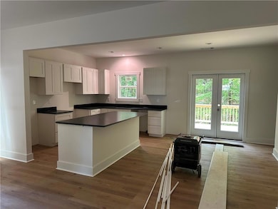 Kitchen with french doors, wood finished floors, baseboards, a center island, and recessed lighting