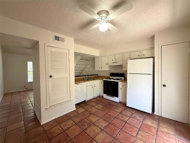 Kitchen with white appliances, a textured ceiling