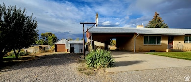 Ranch-style house with a chimney, driveway, brick siding, an outbuilding, and a garage