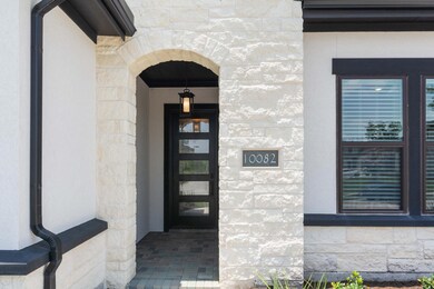 Covered entry features a beautiful wood & privacy glass front door and brick paver porch.