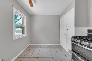 Kitchen featuring white cabinetry, light tile flooring, ceiling fan, and range with two ovens