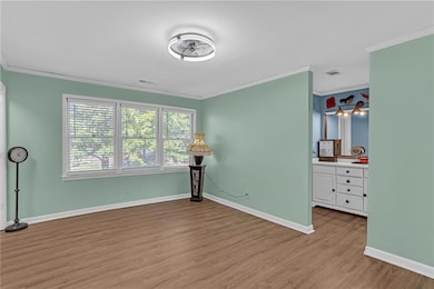 Unfurnished bedroom with ornamental molding and wood finished floors