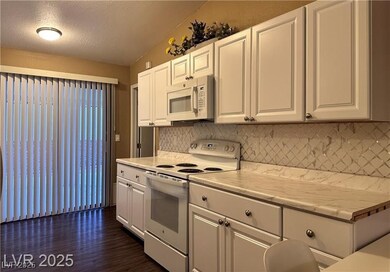Kitchen with white appliances, light countertops, a textured ceiling, white cabinets, and backsplash