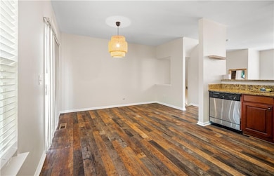 Unfurnished dining area with dark wood-style floors and baseboards