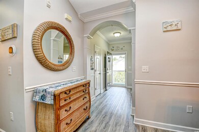Hall featuring crown molding, arched walkways, wood finished floors, and a textured ceiling