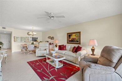 Living room featuring ceiling fan with notable chandelier, visible vents, a textured ceiling, and light tile patterned floors