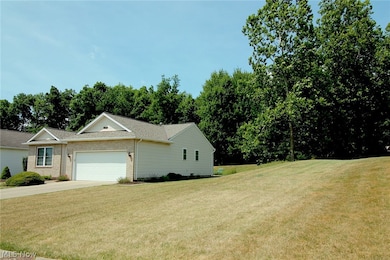 View of side of property with a garage and a lawn
