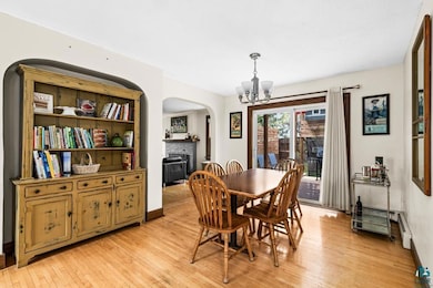 Dining area with arched walkways, a chandelier, a brick fireplace, light wood-type flooring, and baseboards