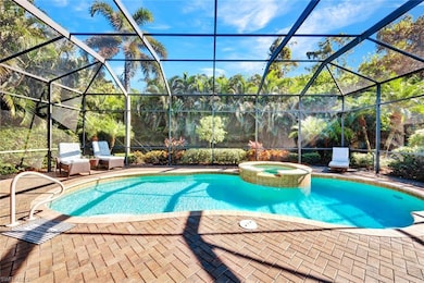 View of pool with connected hot tub, under screened-in lanai surrounded by lush landscaping offering a quiet preserve view.