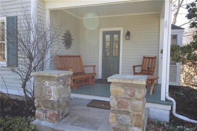 Front porch has stone pillars and seating area.