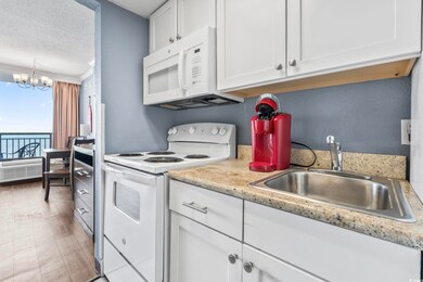Kitchen with white appliances, a textured ceiling,