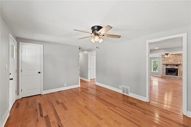 Unfurnished living room featuring hardwood / wood-style floors, ceiling fan, and a fireplace